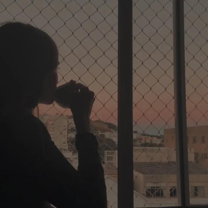 Mujer en silueta frente a la ventana al atardecer